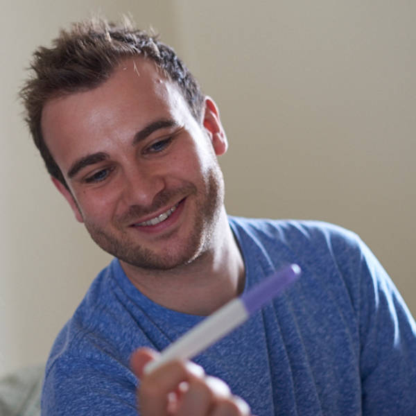 Image of an adult smiling at a pregnancy test.