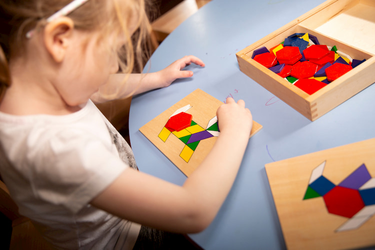 Image of a child sitting at a table, solving a colourful puzzle.