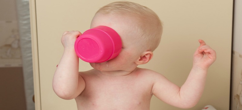 Photo of a baby drinking from a pink plastic cup