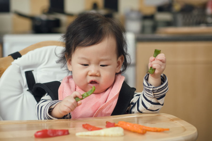 photo of a baby eating in a highchair