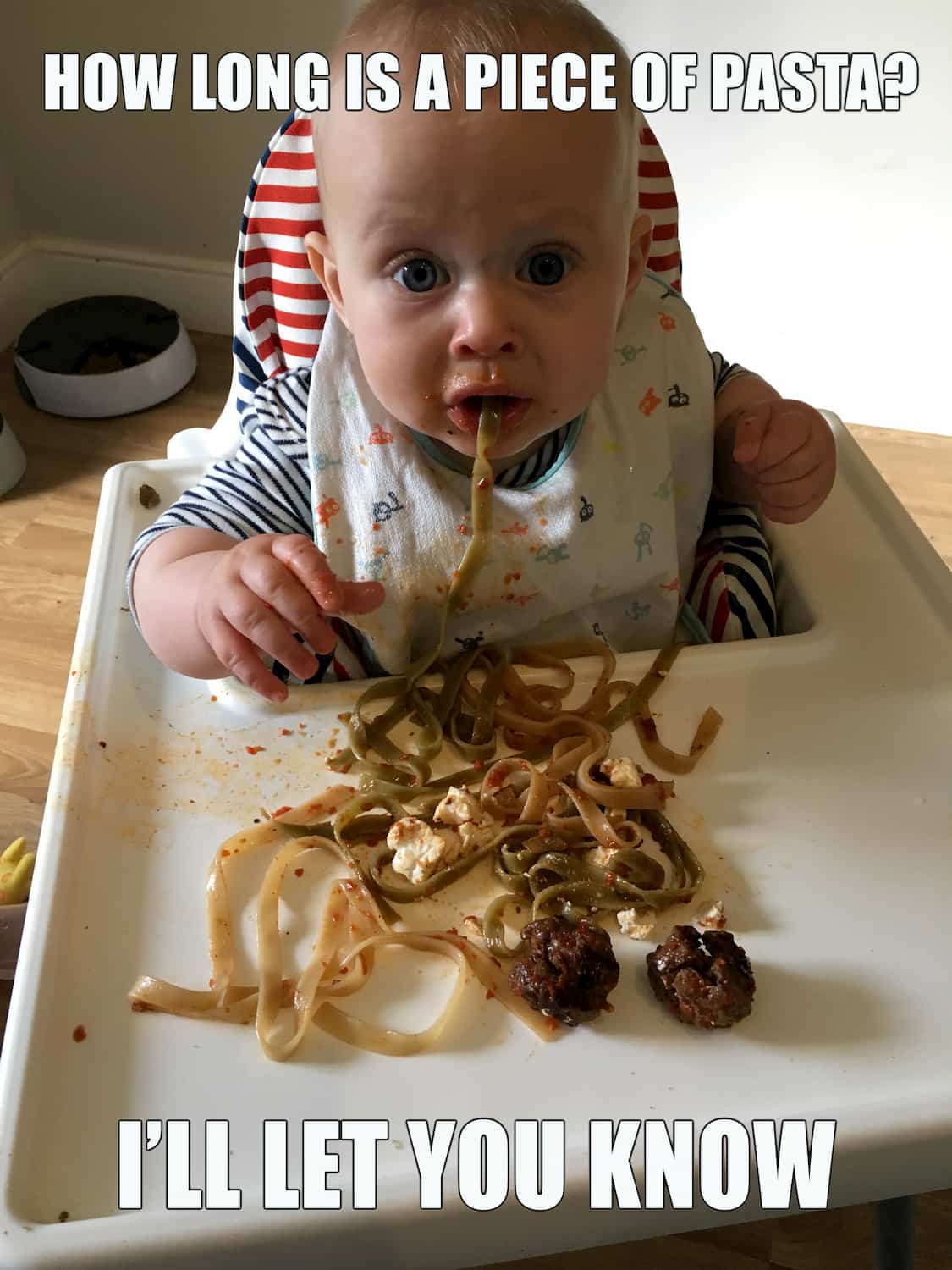 Photo of baby eating a long piece of pasta. Caption: how long is a piece of pasta? I'll let you know