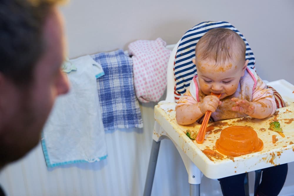 a baby in a highchair messily eating food
