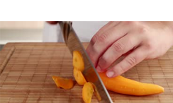 person chopping a carrot on a cutting board