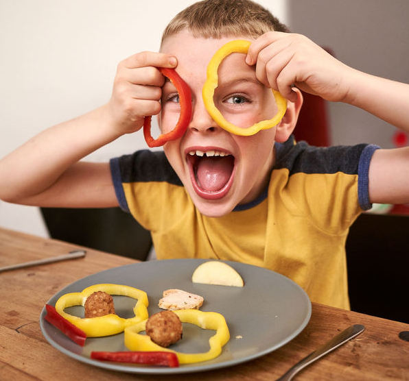child holding cut peppers up to his face like glasses