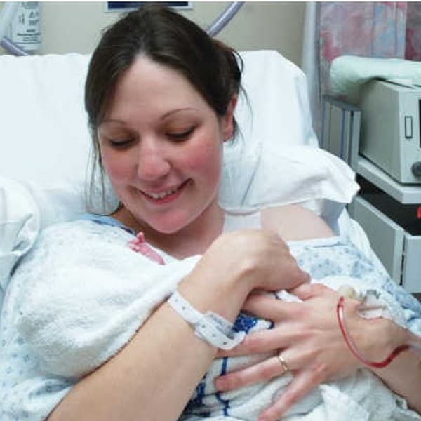 Photo of a mother holding her newborn baby in the hospital post-birth