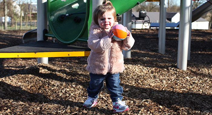 Photo of a toddler playing with a ball in a playground 