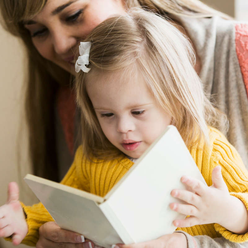 photo of toddler reading with mum
