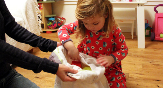 Photo of a child pulling toys out of a bag with parent holding the bag